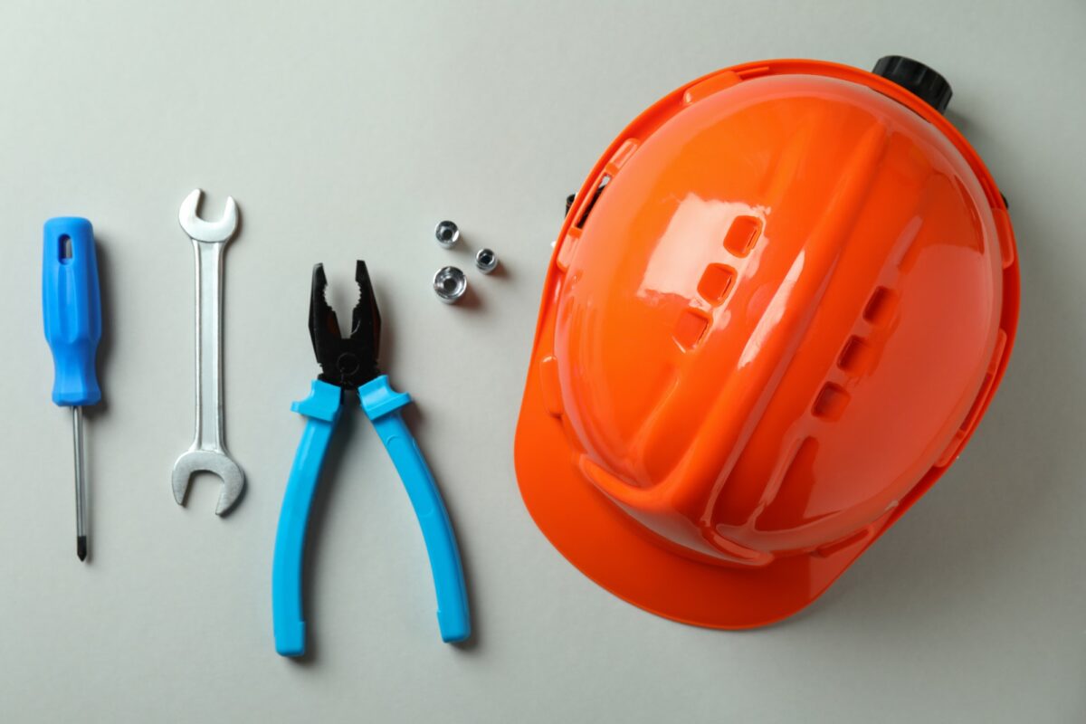 Hard hat and working tools on light gray background